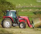 Красный трактор, перевозящих тюков травы